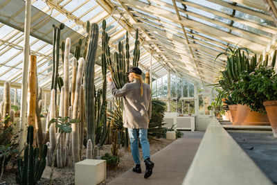 Woman standing next to the cacti and succulent plants inside the greenhouse