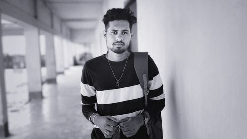 Portrait of young man standing against wall