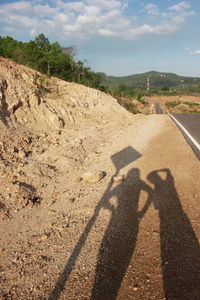 Shadow of couple on road against sky