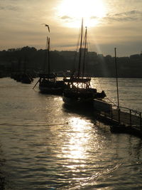 Silhouette boats in calm lake at sunset