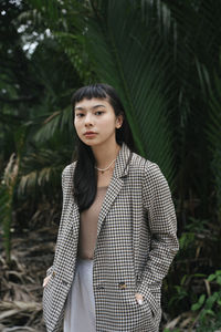 Portrait of young woman standing against plants