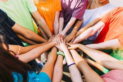 Friends stacking hands on sunny day