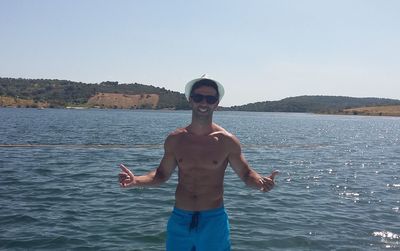 Portrait of young man standing in sea against clear sky