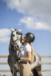 Woman stroking horse while standing in ranch