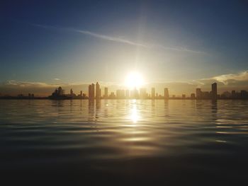 Scenic view of river and buildings against sky during sunset