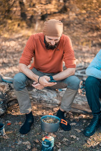 Rear view of man holding hands while sitting on land