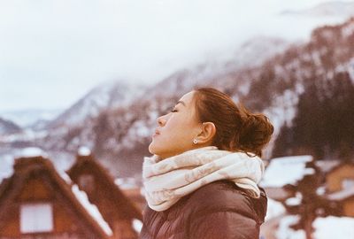 Woman standing on mountain against cloudy sky