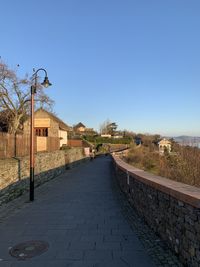 Street amidst buildings against clear blue sky