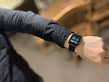 Close-up of hand holding clock against blurred background