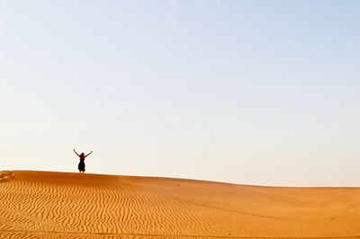 Man standing on sand dune in desert against sky