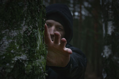 Portrait of man by tree trunk in forest