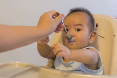 Cropped hand of mother feeding boy at home