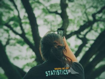 Rear view of woman standing against trees