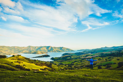 Rear view of man standing on landscape against cloudy sky