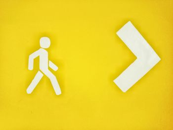Close-up of arrow sign on yellow background