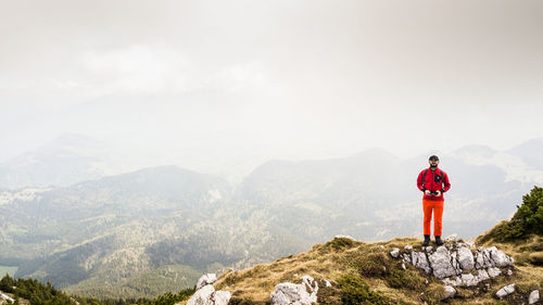 Rear view of man standing on mountain against sky