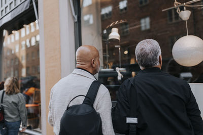 Rear view of senior male friends doing window shopping at street