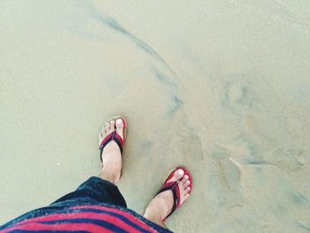 Low section of woman standing on sand
