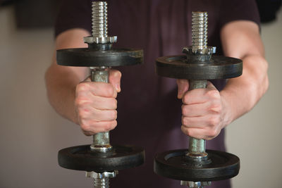 Midsection of man exercising with dumbbells