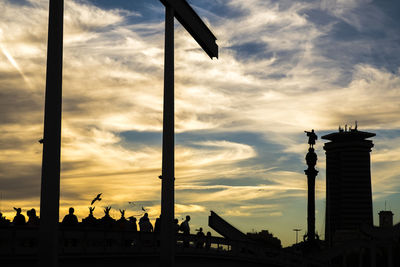 Silhouette rambla del mar bridge at port vell against cloudy sky