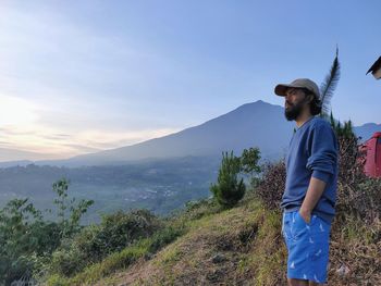 Young man standing on mountain against sky