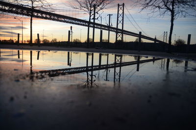 Bridge over river against sky at sunset