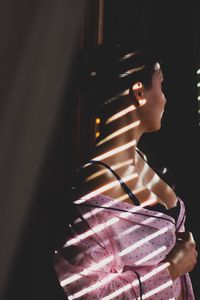 Side view of seductive woman standing in darkroom