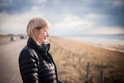 Side view of senior woman wearing warm clothing while looking away against sky