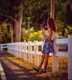 Woman taking selfie while standing on footpath