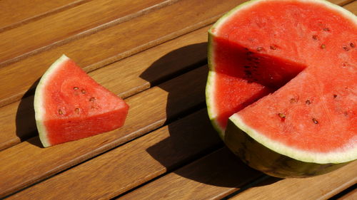 High angle view of watermelon and slice on wooden table