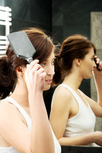 Close-up of woman combing hair by mirror