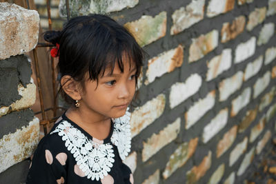 Smiling girl standing by stone wall