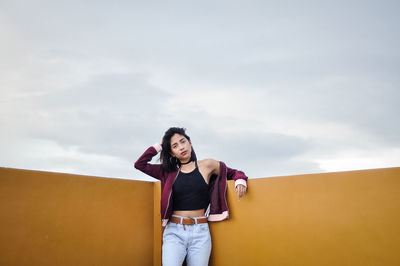 Low angle view of young woman standing against sky