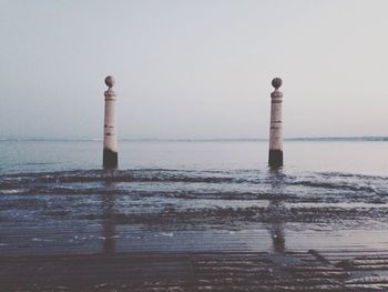 Poles amidst sea against sky