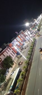 High angle view of illuminated street amidst buildings in city at night