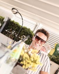 Portrait of young woman wearing sunglasses while standing in greenhouse