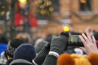 Midsection of man amidst crowd photographing in city