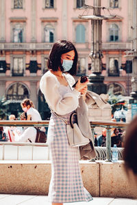 Midsection of woman holding umbrella while standing in city