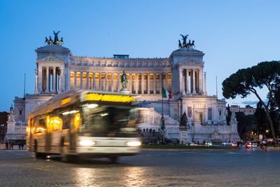 Blurred motion of bus on road against historic building in city