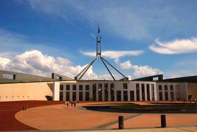 People outside parliament house against sky