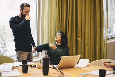 Happy business colleague looking at each other during meeting in board room