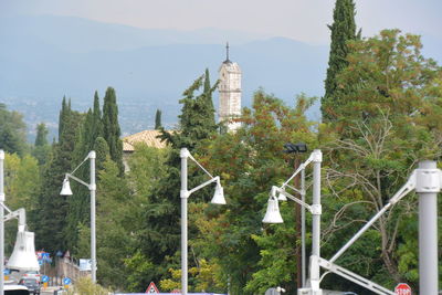 Panoramic view of street lamps and trees against sky