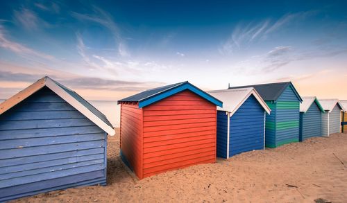 Colourful beach huts against sky and sand