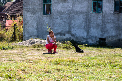 Full length of woman with dog sitting outdoors