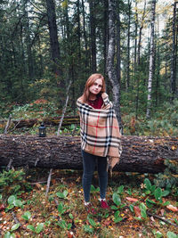 Portrait of woman wrapped in scarf standing against trees in forest