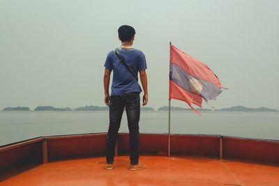 Rear view of man looking at sea against sky