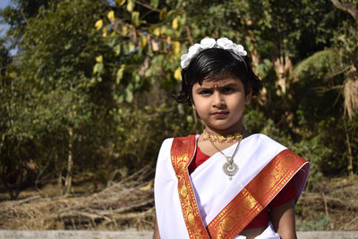 Portrait of girl in traditional clothing against plants