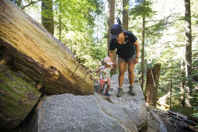 Full length of woman standing on rock in forest