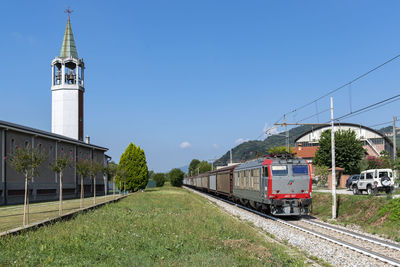 Train on railroad tracks amidst buildings against clear sky