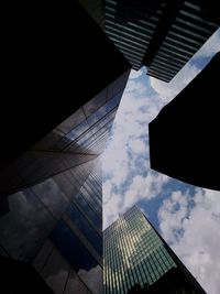 Low angle view of skyscrapers against cloudy sky